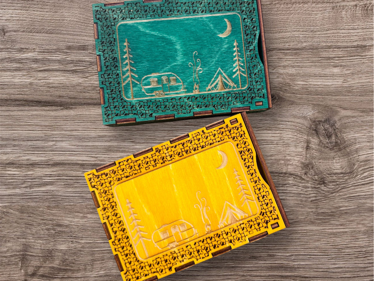 Two decorative travel size  cribbage boards cards size with engraved designs on a wooden surface